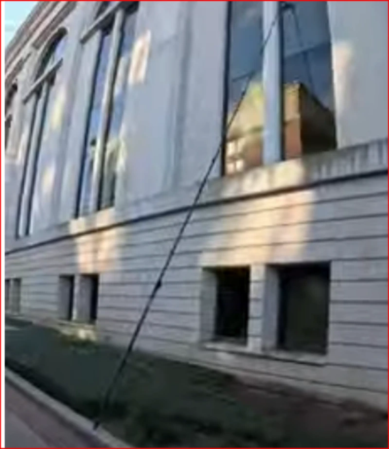 Window cleaner using a water-fed pole to reach the upper windows of a commercial building