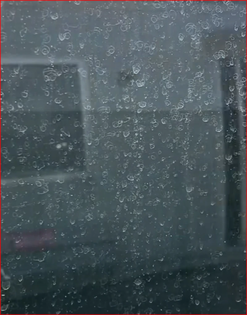 Close-up of water spots and droplet marks scattered across a window pane