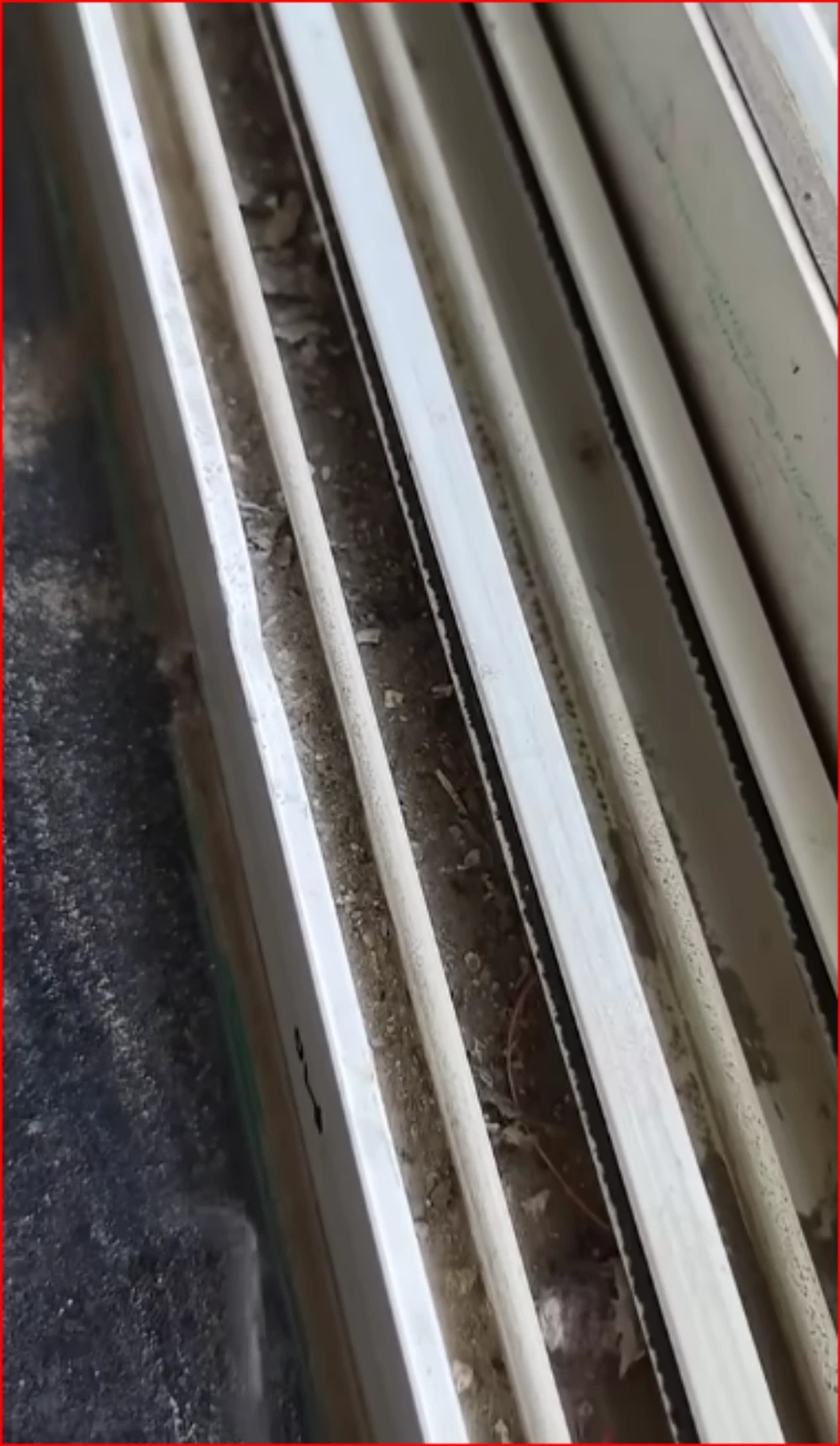 Close-up of a sliding window track packed with dust, grit and debris before cleaning
