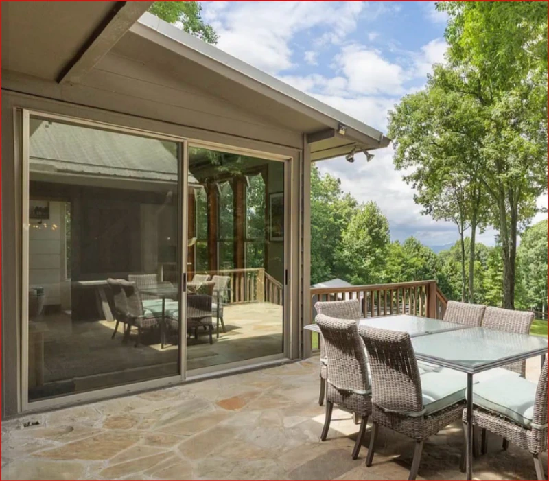 Large sliding glass doors opening onto a covered patio with tree views
